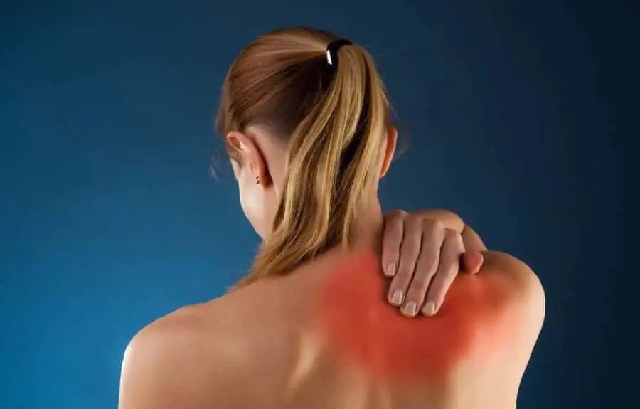 Back view of a woman holding with a pinched nerve at her right shoulder blade. Treatment available at Hinze Chiropractic and Acupuncture in Columbus